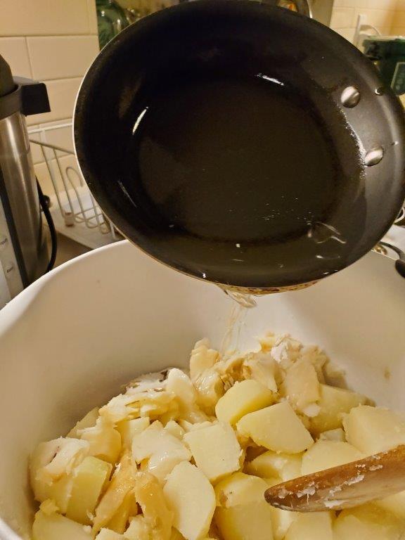 Oil being poured over fish and potatoes